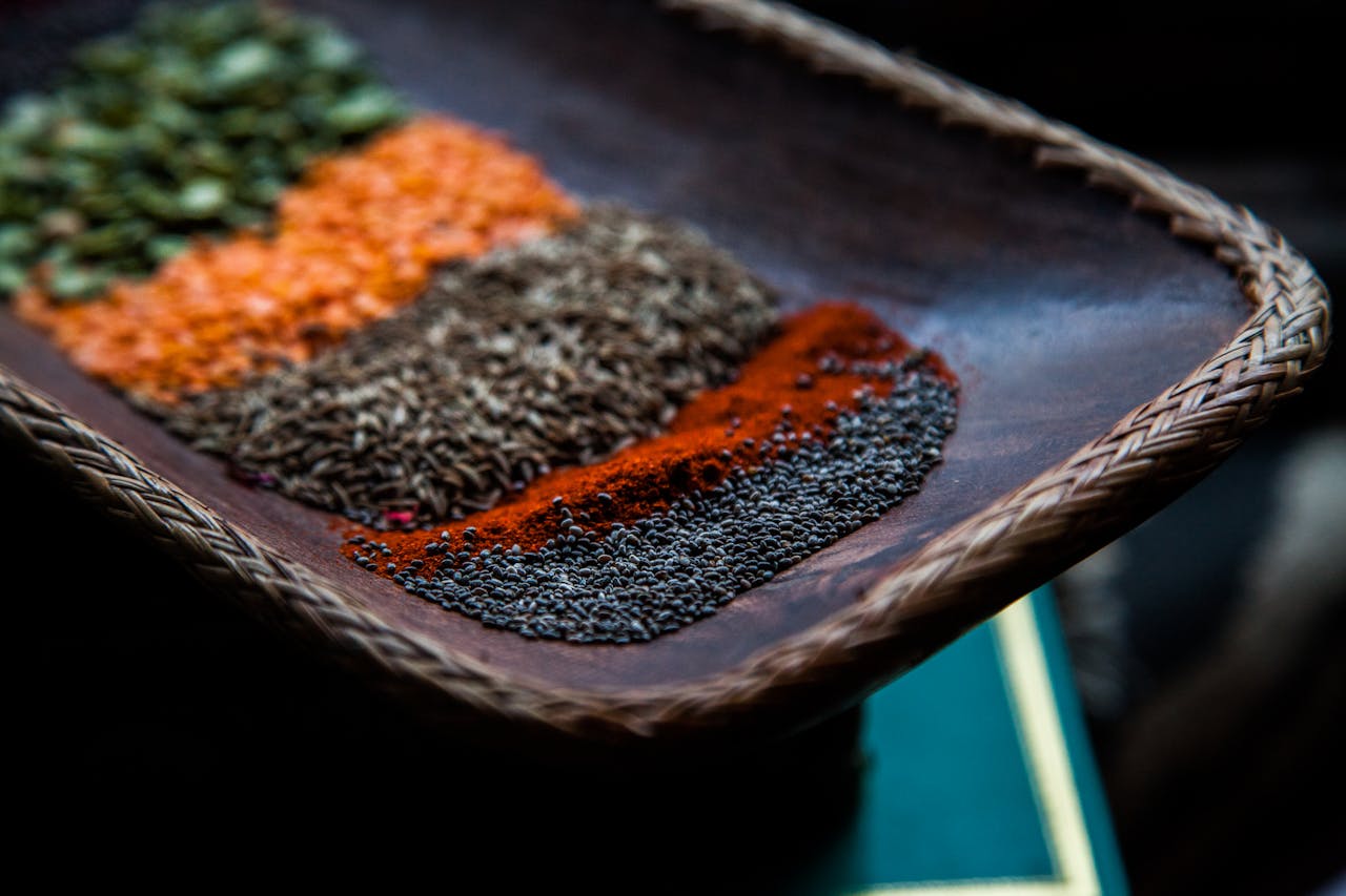 ours-journey Close-up of colorful Indian spices arranged on a wicker tray, showcasing diverse flavors.